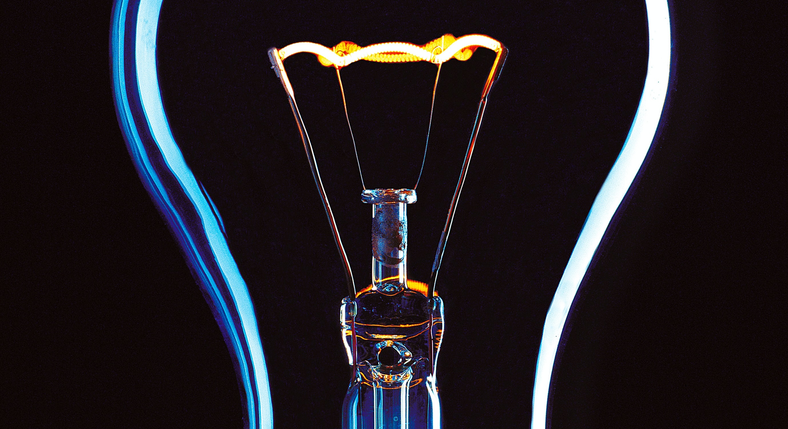 A photo of a lightbulb with a glowing filament against a black background.